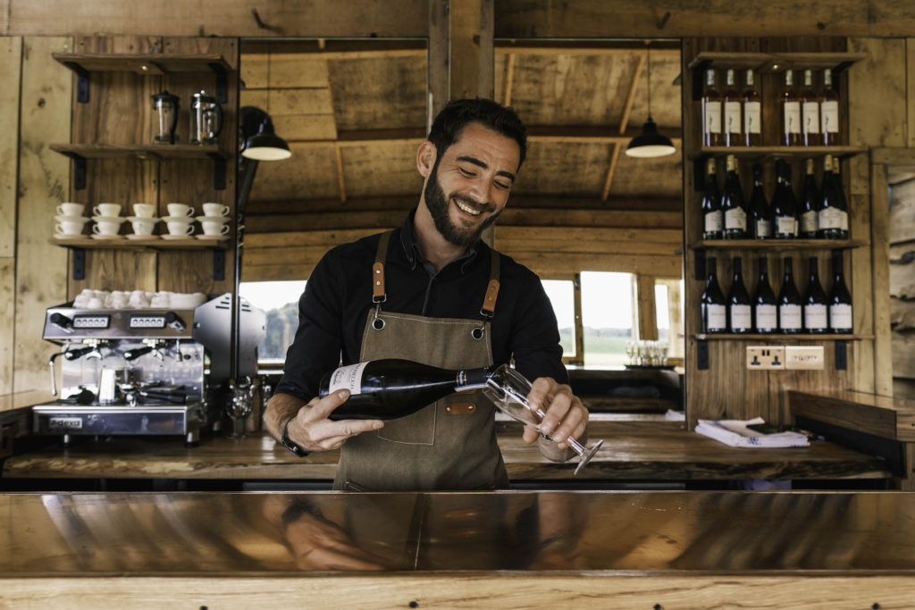 Barman pouring a glass of red wine.